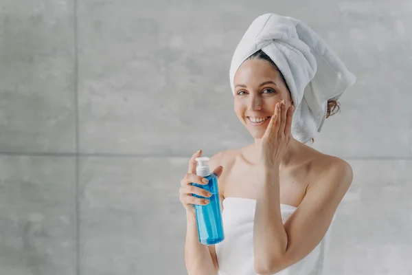タオルを巻いた女性が青いボトルを持って化粧水を塗っている - スキンケアで化粧水を使うタイミングは? 2026 - Zicail タオルを巻いた女性が青いボトルを持って化粧水を塗っている - スキンケアで化粧水を使うタイミングは? 2026 - Zicail