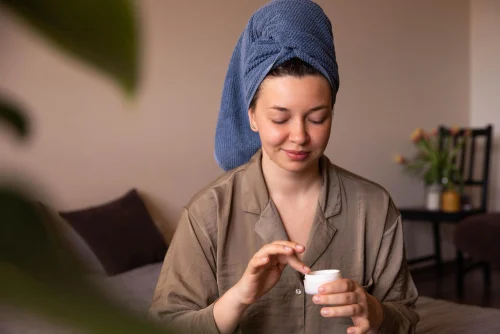 Woman applying Snail Mucin cream with a towel on her head - Snail Mucin in Skincare: Benefits, Usage, and Advice - Zicail