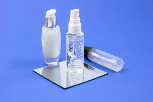 Three cosmetic serum bottles on a blue background - Toner vs Essence: Differences & Which One You Need - Zicail Three cosmetic serum bottles on a blue background - Toner vs Essence: Differences & Which One You Need - Zicail