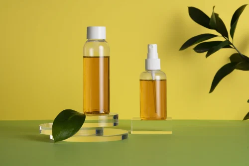 Two amber colored skincare bottles with green leaves - Toner vs Essence: Differences & Which One You Need - Zicail Two amber colored skincare bottles with green leaves - Toner vs Essence: Differences & Which One You Need - Zicail
