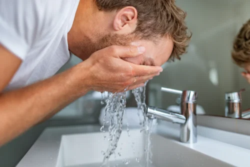 男性が洗面台で顔を水で洗っている - 髭剃りの前に顔を洗うべきか、後に洗うべきか？ 2026 - Zicail