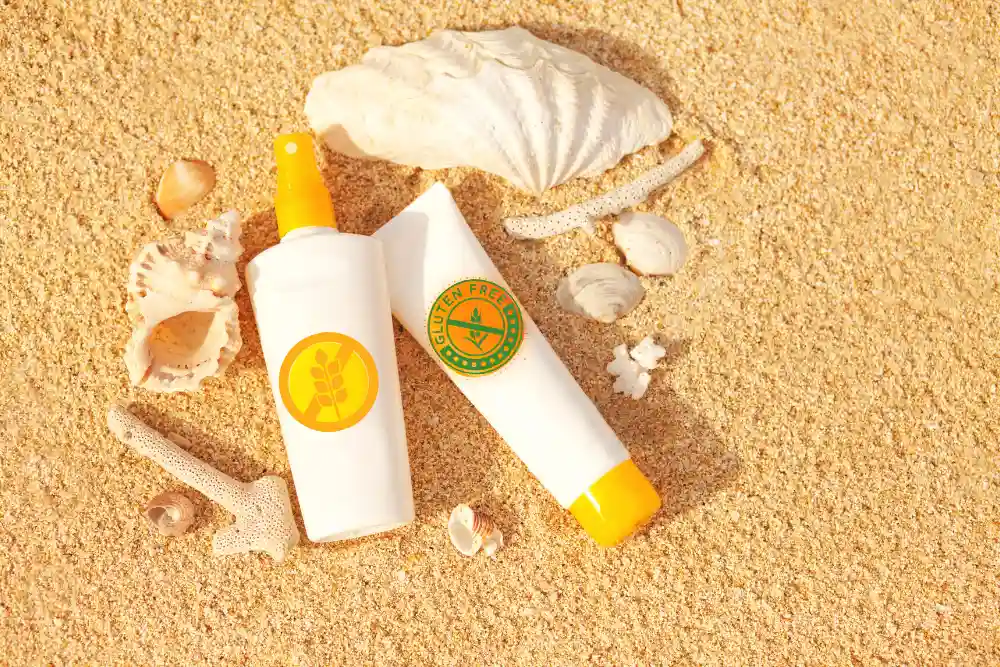 Sunscreen bottles with gluten free logos on a sandy background