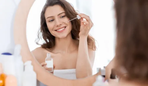 Woman applying a serum with a dropper in front of a mirror - How to Apply Toner Correctly (Step-by-Step Guide) 2026 - Zicail