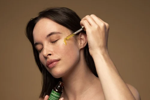 Woman applying golden serum with a dropper to her cheek - Natural Skincare Routine: Simple Steps for Healthy Skin [October 2026] - Zicail