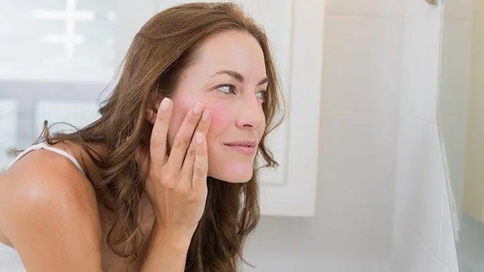 Woman examining red sensitive skin in the mirror - Polyhydroxy Acid in Skincare: Benefits, Uses, and How It Works 2026 - Zicail Woman examining red sensitive skin in the mirror - Polyhydroxy Acid in Skincare: Benefits, Uses, and How It Works 2026 - Zicail