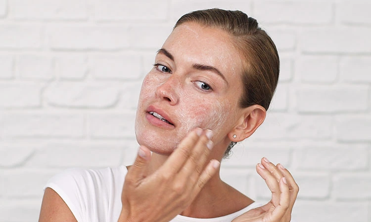 Woman gently exfoliating her face with a skincare product - What Are The 5 Basic Of Skin Care? 2026 - Zicail Woman gently exfoliating her face with a skincare product - What Are The 5 Basic Of Skin Care? 2026 - Zicail