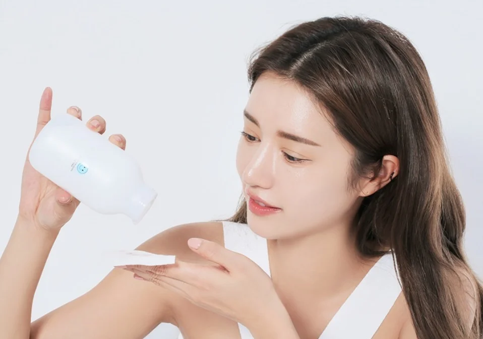 Woman pouring skincare product onto a cotton pad - What Are The 5 Basic Of Skin Care? 2026 - Zicail Woman pouring skincare product onto a cotton pad - What Are The 5 Basic Of Skin Care? 2026 - Zicail