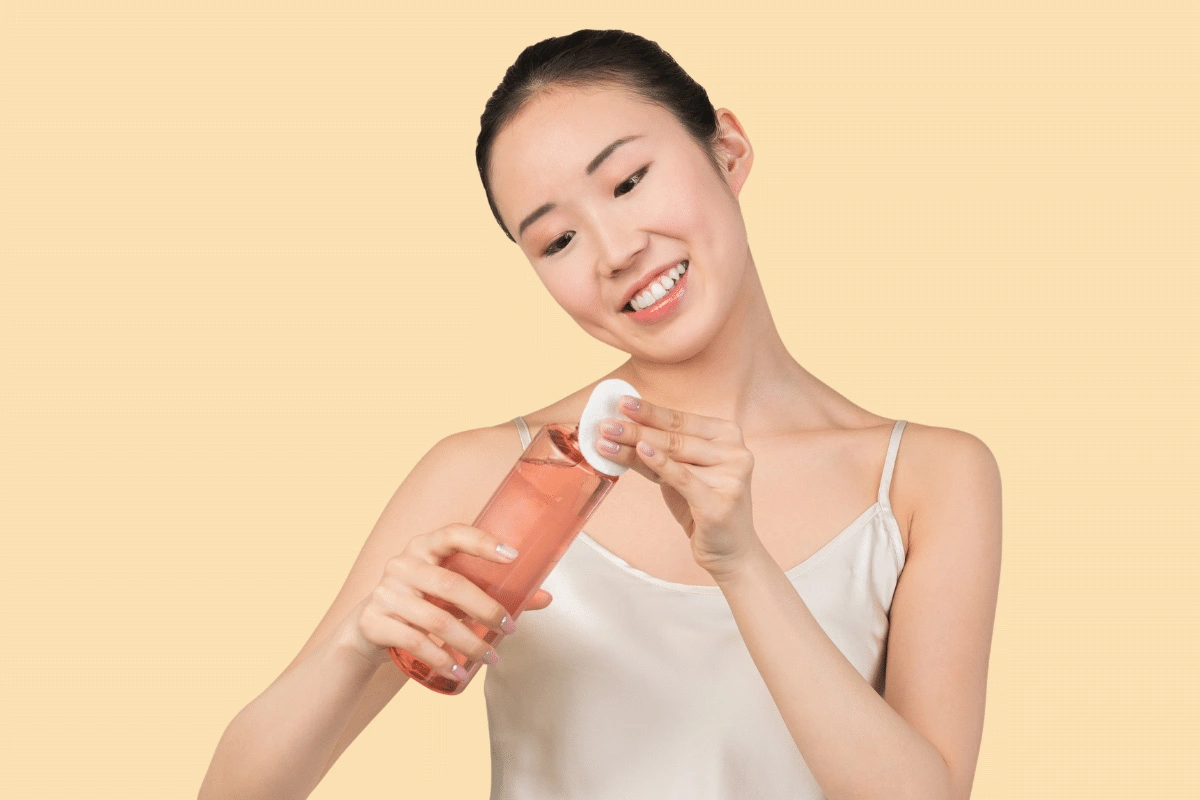 Woman pouring toner onto cotton pad with a smile - Skincare for Beginners: A Simple Way to Get Started [October 2026] - Zicail