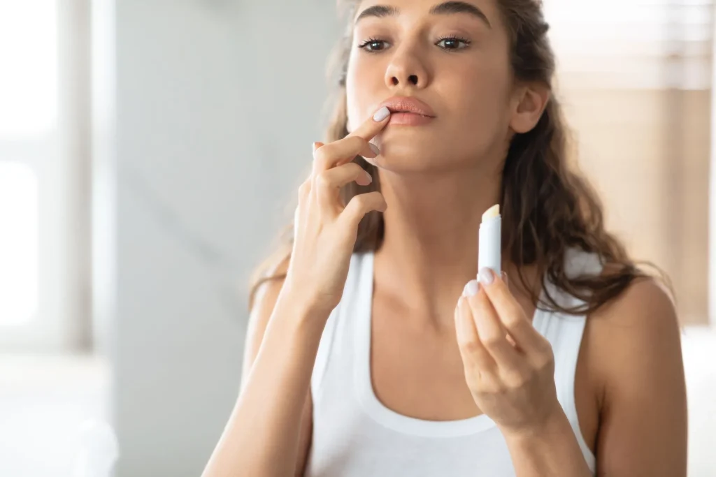 Woman using lip balm looking in mirror