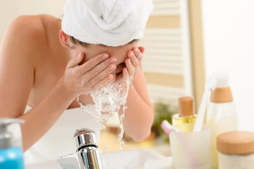 Woman washing her face at a sink with water splashing - How to Apply Toner Correctly (Step-by-Step Guide) 2026 - Zicail