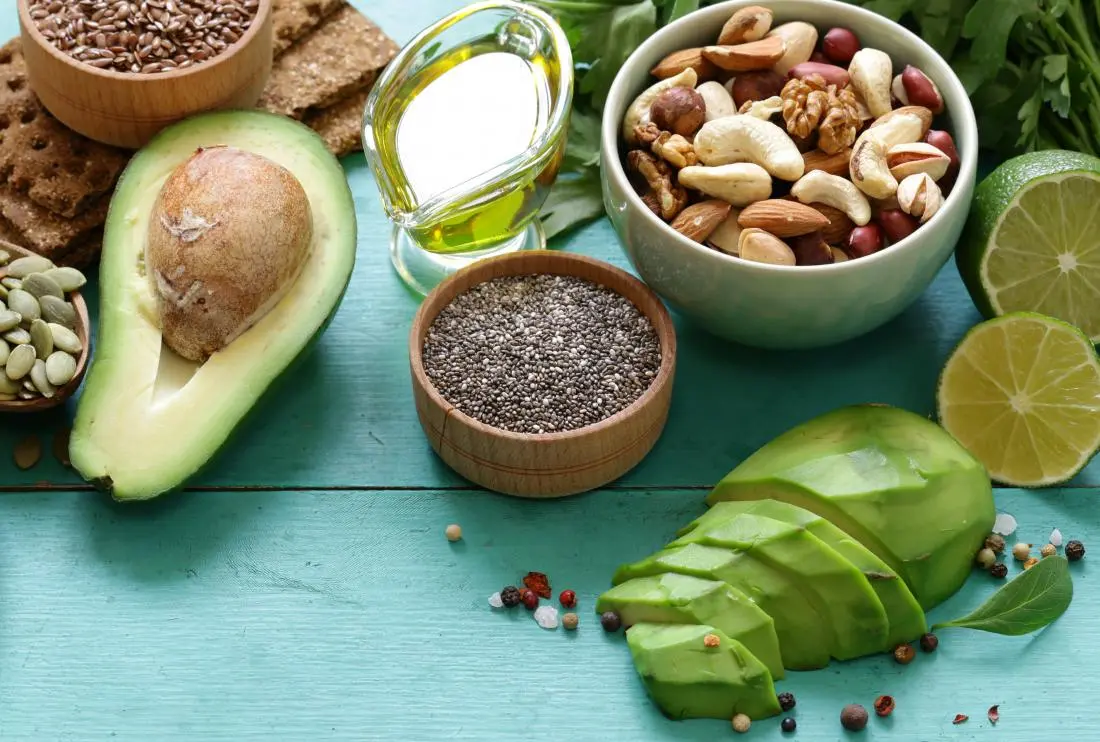 A selection of skin nourishing foods including avocado nuts seeds lime and olive oil on a teal table - Why Body Wash Makes Skin Oily & How to Fix It 2026 - Zicail
