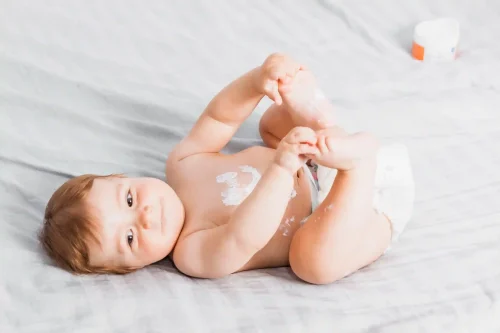 Baby applying lotion on feet smiling - Baby Lotion vs Baby Oil: Which Is Best for Your Baby’s Skin? 10月 2026 - Zicail
