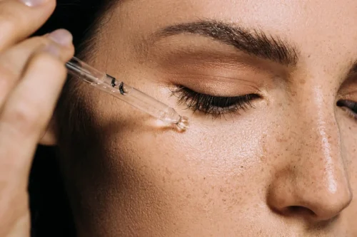 Close up of a dropper applying serum near a womans eye - How to Use Vitamin C and Hyaluronic Acid Together for Better Skin 2026 - Zicail