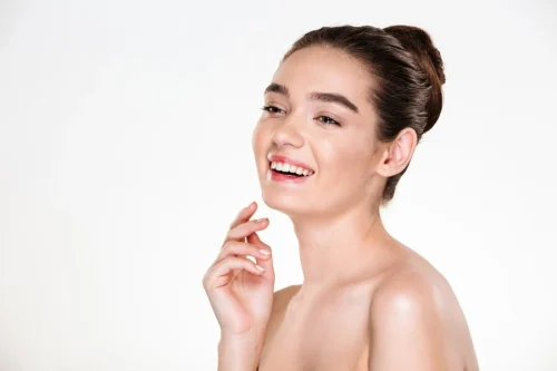 白い背景の前でポーズをとる、透明感のある輝く肌の笑顔の女性 - 透明感のある肌を手に入れる方法：健康的で輝く肌のためのヒント 2026 - Zicail