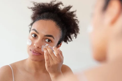 鏡を見ながら顔に優しく保湿クリームを塗る女性 - 傷跡クリームの仕組みとは？効果と主要成分を解説 2026 - Zicail