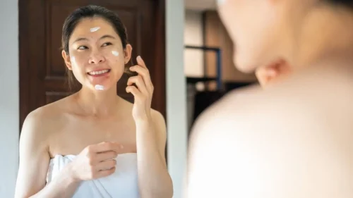 バスルームで笑顔で顔にクリームを塗る女性 - 傷跡クリームの仕組みとは？効果と主要成分を解説 2026 - Zicail