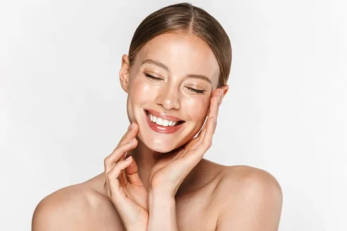 A smiling woman touching her face highlighting skincare results - How to Layer Hyaluronic Acid and Lactic Acid 2026 - Zicail