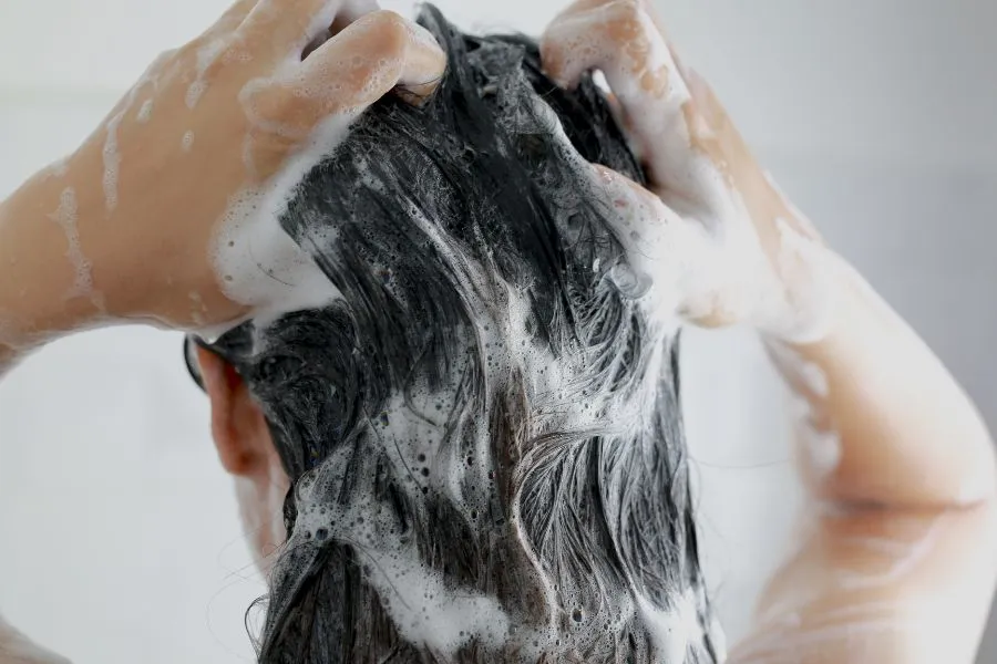 A woman with black hair applying shampoo while washing her hair - How to Treat and Manage Oily Hair？ 2026 - Zicail