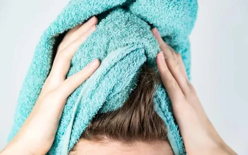 タオルで包んだ手がストレートヘアを乾かしているクローズアップ - 完璧なストレートヘアを手に入れる方法:プロのヒントとコツ 2026 - Zicail タオルで包んだ手がストレートヘアを乾かしているクローズアップ - 完璧なストレートヘアを手に入れる方法:プロのヒントとコツ 2026 - Zicail
