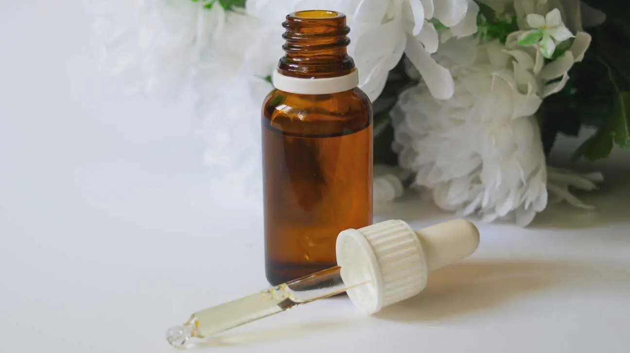 Hair oil bottle with dropper beside white flowers - Hair Serum vs Hair Oil: Which One Does Your Hair Need? October 2026 - Zicail