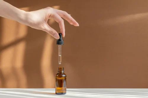 Hand dropping hyaluronic acid into a glass bottle - How to Layer Hyaluronic Acid and Lactic Acid 2026 - Zicail