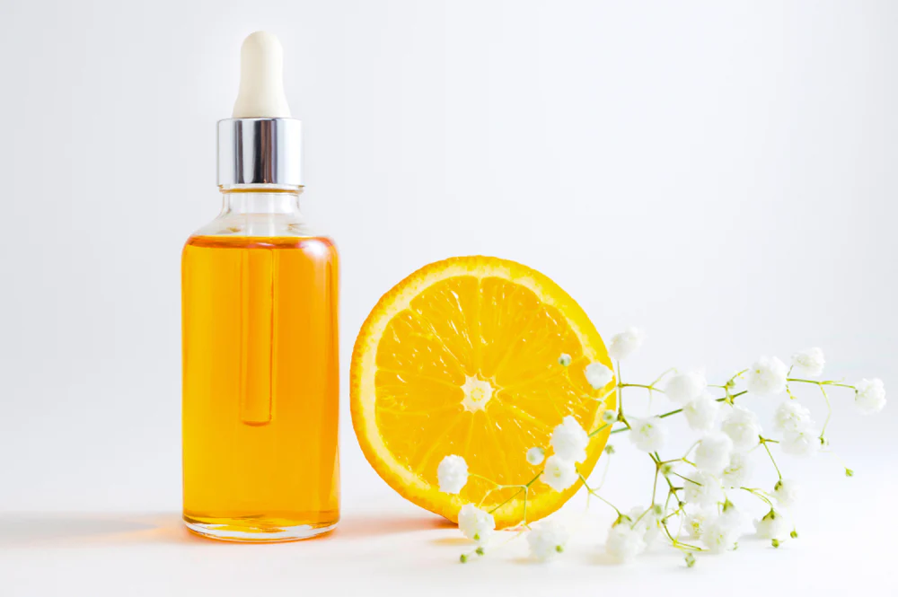 Vitamin C serum bottle with sliced orange and flowers - Azelaic Acid vs Vitamin C: Benefits & Use Guide 2026 - Zicail