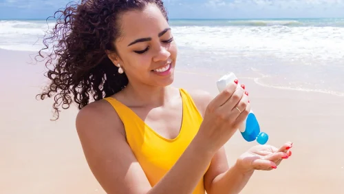 Woman applying sunscreen at the beach - Reef-Safe Sunscreen: What It Means & How to Choose 2026 - Zicail Woman applying sunscreen at the beach - Reef-Safe Sunscreen: What It Means & How to Choose 2026 - Zicail
