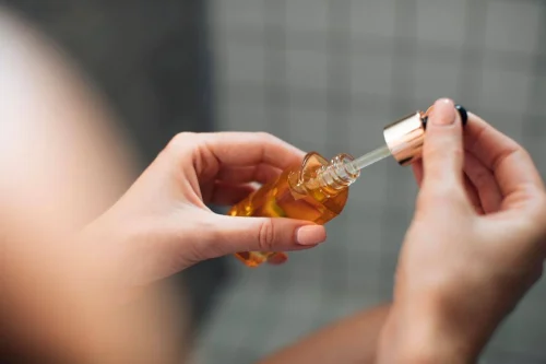 Woman holding a dropper bottle of Vitamin C oil - How to Use Vitamin C and Hyaluronic Acid Together for Better Skin 2026 - Zicail