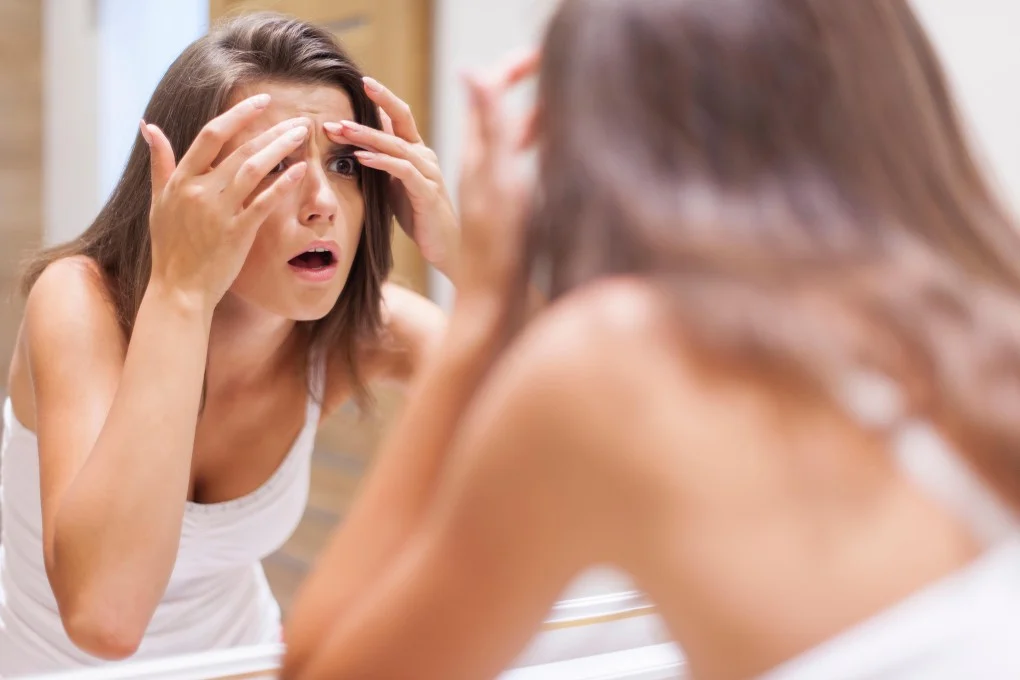 Woman in front of a mirror applying products for acne relief - Grapeseed Oil for Skin: Benefits & How to Use 2026 - Zicail