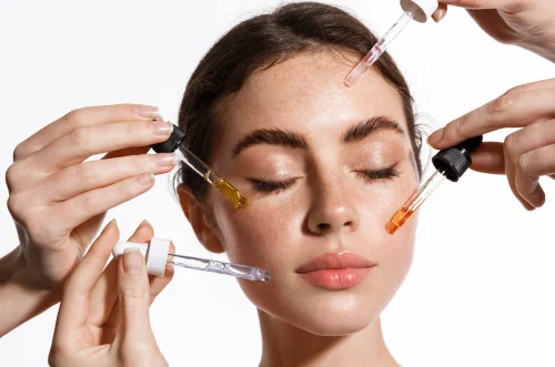 Woman with multiple droppers applying Vitamin C serum - How to Layer Hyaluronic Acid and Lactic Acid 2026 - Zicail