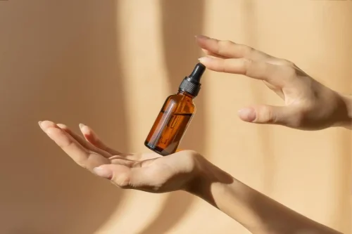 holding a dropper bottle of Vitamin C oil - How to Use Vitamin C and Hyaluronic Acid Together for Better Skin 2026 - Zicail