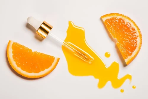 Fresh orange juice paired with an oil dropper emphasizing vitamin C - Is Vitamin C Good Under Makeup? Tips for Glowing Skin 2026 - Zicail
