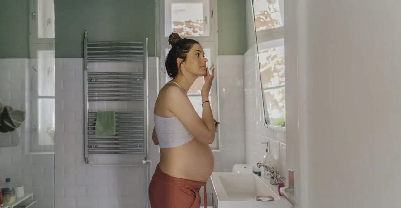 Pregnant woman applying skincare in front of a bathroom mirror - Pregnancy-Safe Skin Care: Expert Advice on Products to Use 2026 - Zicail Pregnant woman applying skincare in front of a bathroom mirror - Pregnancy-Safe Skin Care: Expert Advice on Products to Use 2026 - Zicail