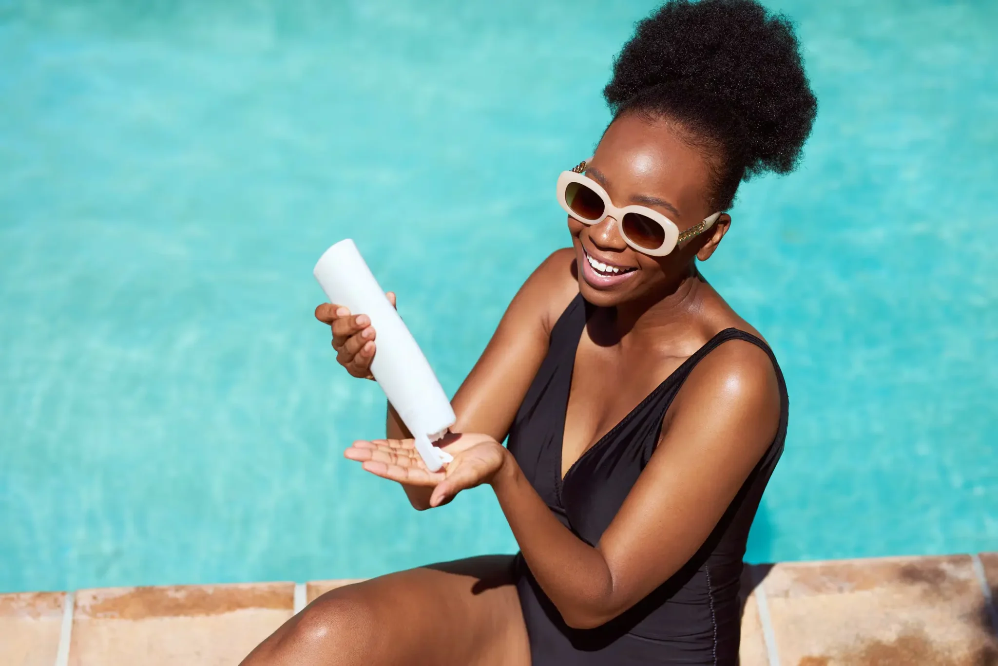 Woman smiling by pool applying sunscreen to hand