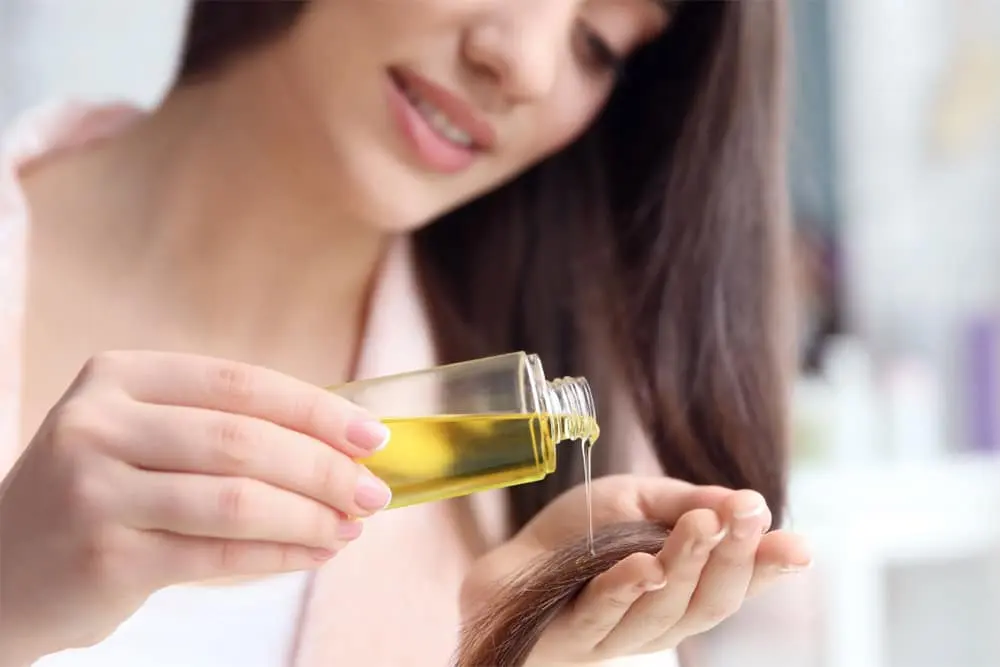 Woman pouring Batana Oil onto hair - Hair Serum vs Hair Oil: Which One Does Your Hair Need? October 2026 - Zicail