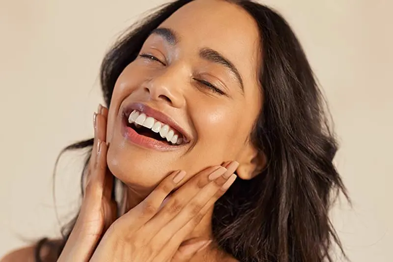 A smiling woman massaging her face reflecting skin care happiness and nourishment - Oleic Acid for Skin: Benefits, Risks & Best Oils 2026 - Zicail A smiling woman massaging her face reflecting skin care happiness and nourishment - Oleic Acid for Skin: Benefits, Risks & Best Oils 2026 - Zicail