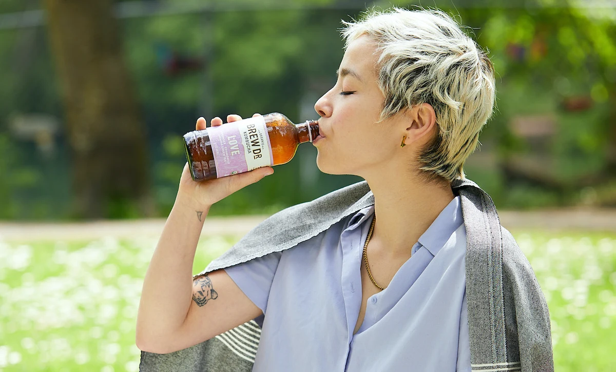 Woman drinking bottled kombucha outdoors for wellness - Kombucha for Skin: Complete Benefits Guide 2026 - Zicail Woman drinking bottled kombucha outdoors for wellness - Kombucha for Skin: Complete Benefits Guide 2026 - Zicail