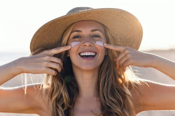 Smiling woman in sunhat applying sunscreen cream to her face - Gel vs Cream Sunscreen: Choose What’s Best 2026 - Zicail Smiling woman in sunhat applying sunscreen cream to her face - Gel vs Cream Sunscreen: Choose What’s Best 2026 - Zicail