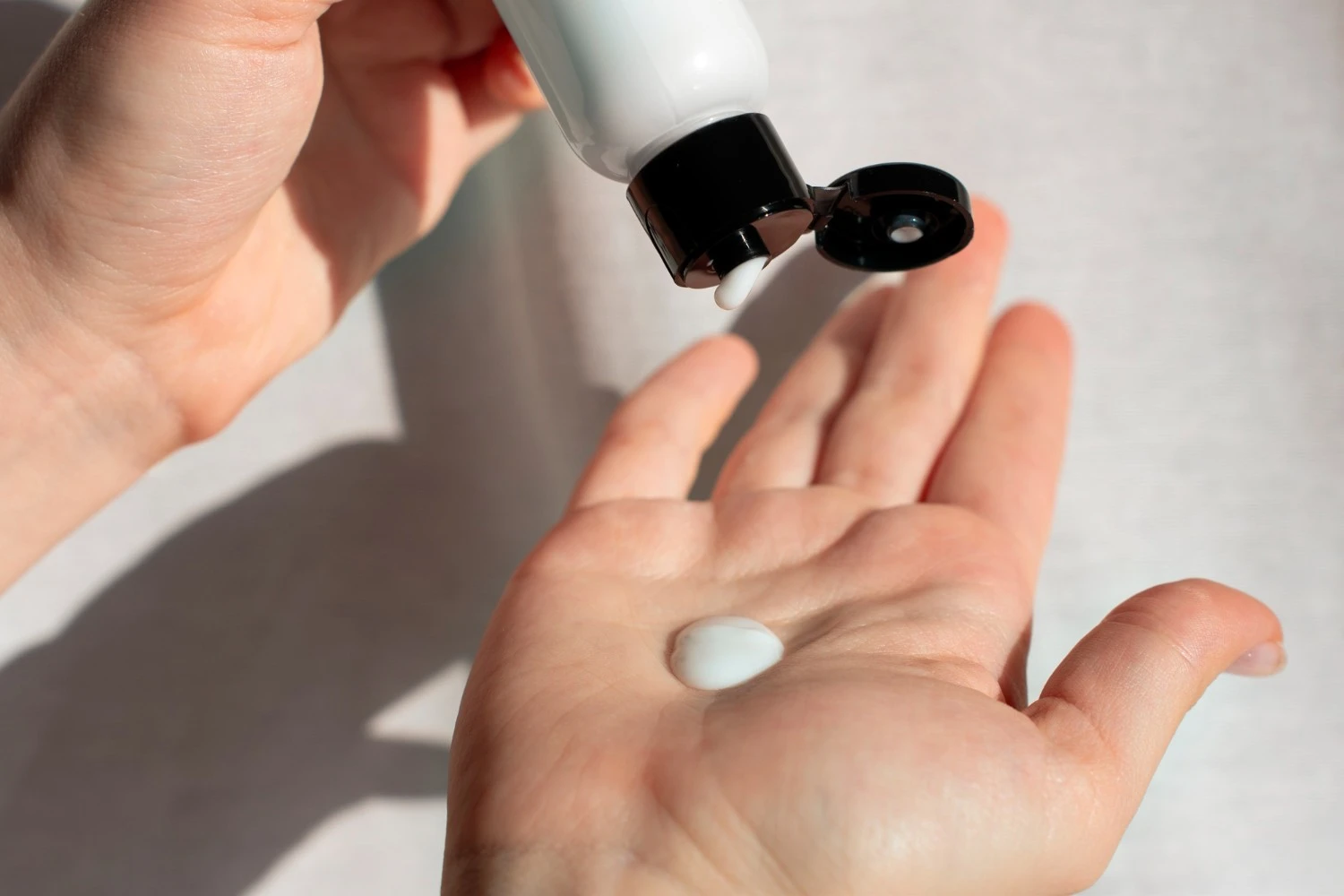 Hand dispensing a smooth lotion like skincare product representing how fatty alcohols contribute to spreadability and comfortable skin feel - Fatty Alcohols in Skincare: Safe or Not? 2026 - Zicail