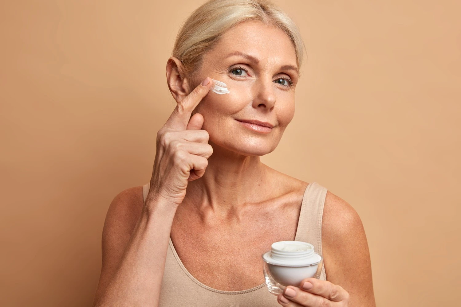 Mature woman applying face cream during daily skincare routine for hydration and skin comfort - Astaxanthin for Skin: Benefits, Uses & How It Works 2026 - Zicail