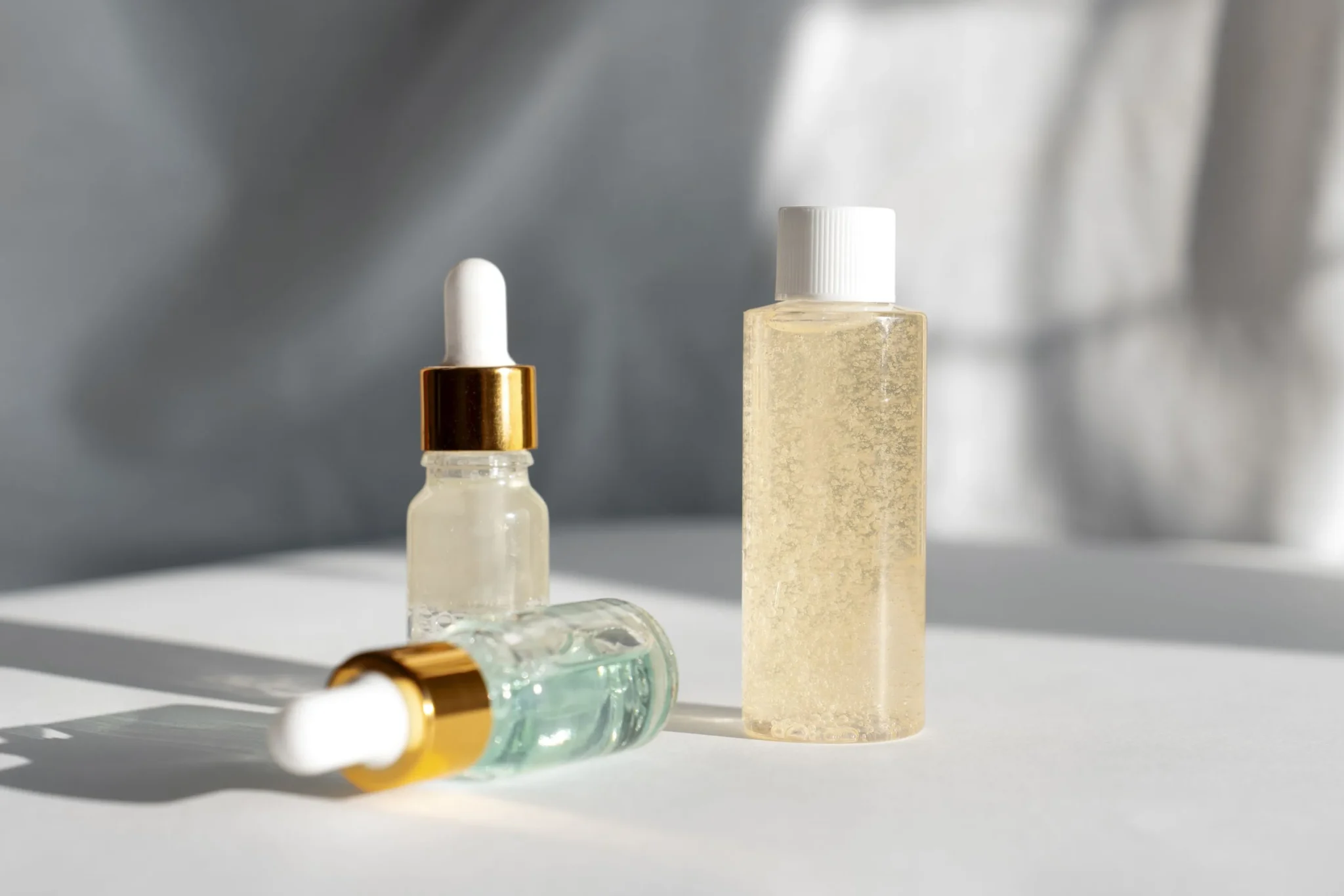 Serum and essence bottles on white surface showing skincare texture differences